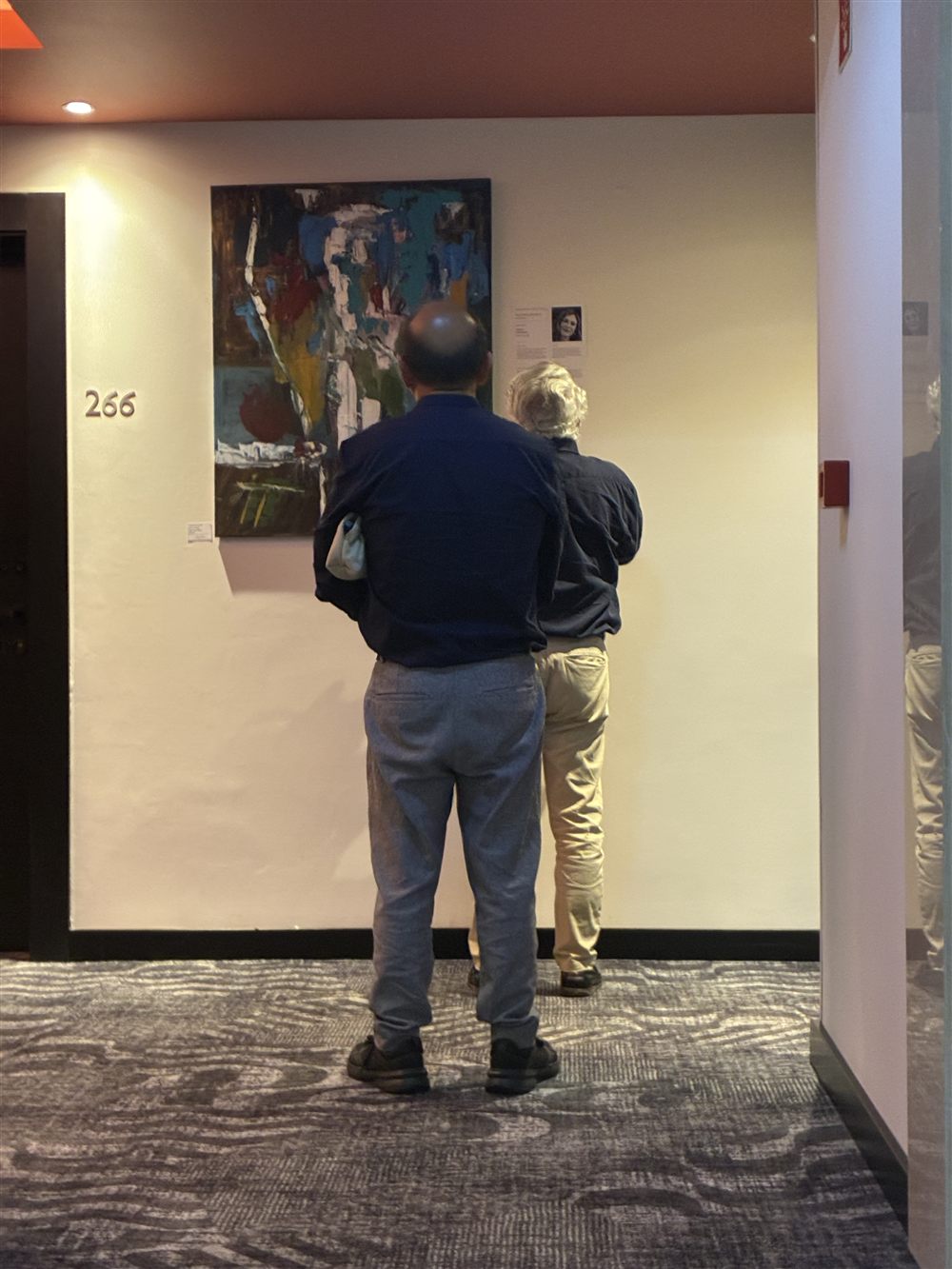 Visitantes a ver uma pintura de Cecília Vilas Boas no corredor do Hotel Avani, na exposição Percursos Abstratos