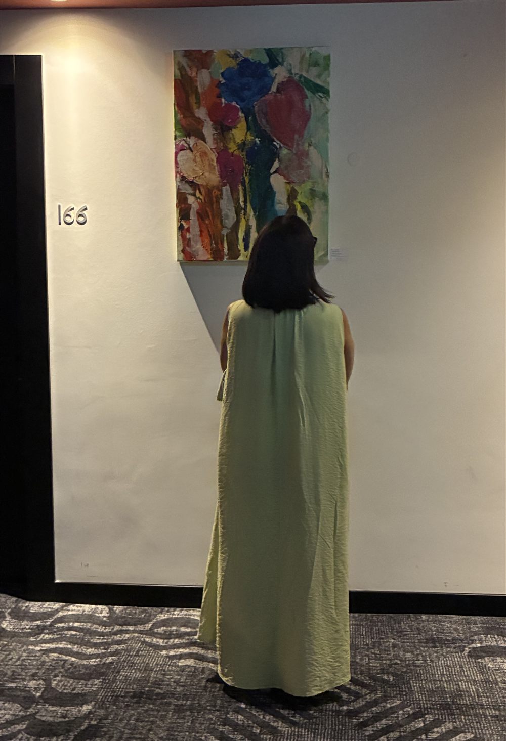 Visitante a ver uma pintura de Cecília Vilas Boas no corredor do Hotel Avani, na exposição Percursos Abstratos